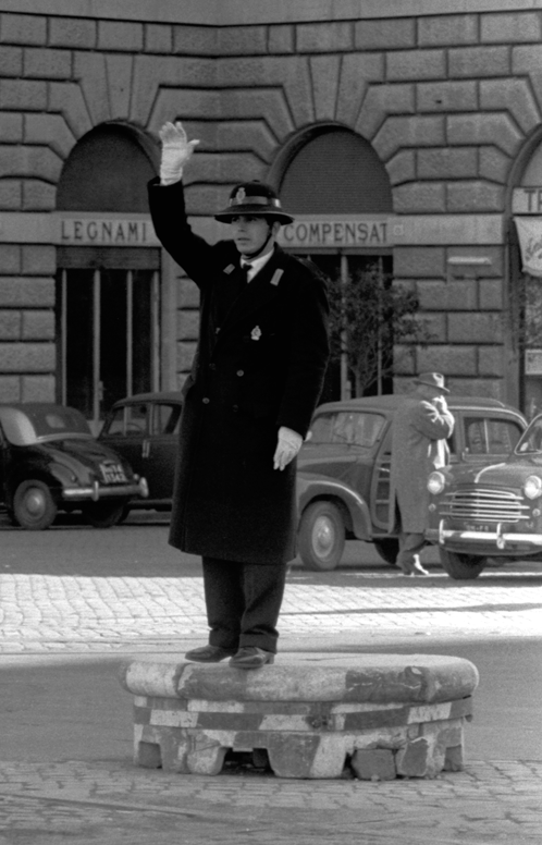 Policeman guiding traffic at crossroad standing on raised platform